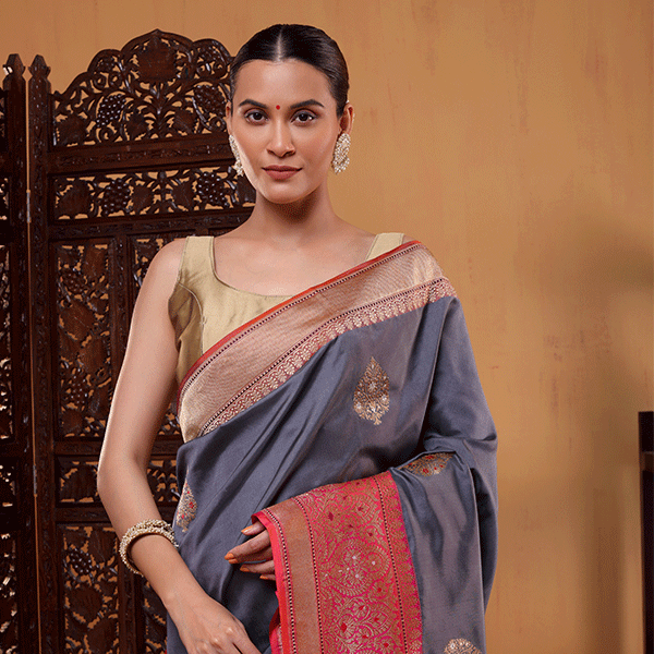 A model wearing the Twilight Radiance pure katan silk saree featuring handwoven gold and silver sauna rupa bootas, a contrasting grey and pink border, and a gold blouse.