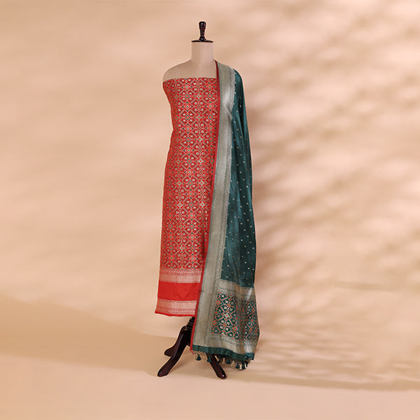 Handwoven pure Patola Banarasi silk unstitched suit featuring a verdant green and gold base with an elegant carrot red multicoloured dupatta.