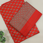 A beautiful flat-lay view of a vibrant red Banarasi silk saree featuring intricate gold zari floral motifs and a rich traditional border, displayed on a neutral background.