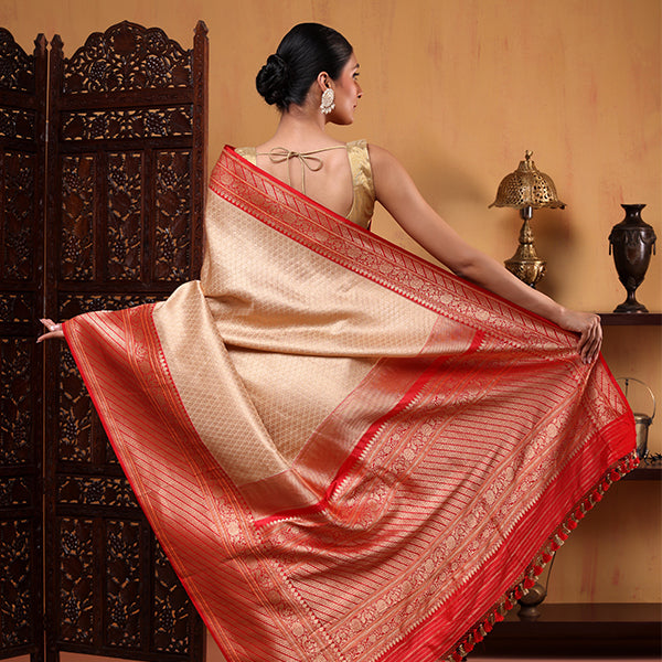 Back view of a white handwoven Banarasi silk saree featuring a heavy red and gold zari pallu, paired with a matching red blouse with gold jaal work.